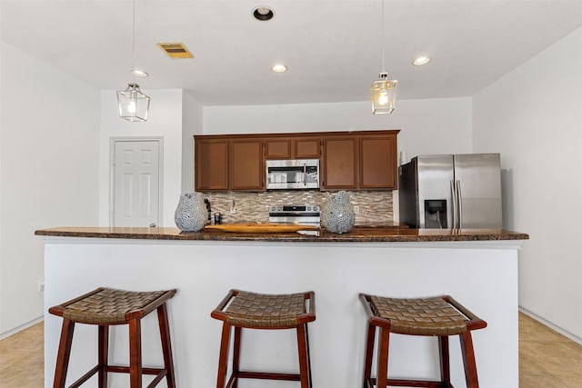 kitchen featuring hanging light fixtures, visible vents, stainless steel appliances, and decorative backsplash