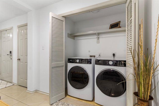 clothes washing area featuring light tile patterned floors, laundry area, and washing machine and clothes dryer