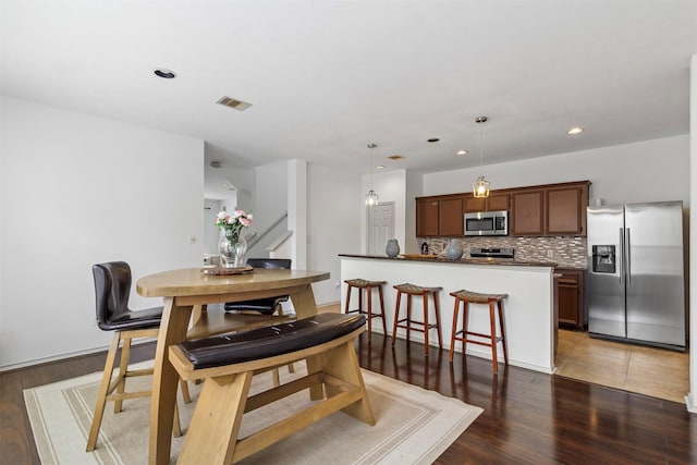 dining area featuring stairs, visible vents, wood finished floors, and recessed lighting