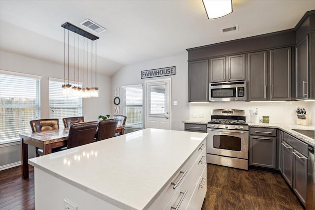 kitchen featuring a center island, decorative light fixtures, stainless steel appliances, light countertops, and visible vents