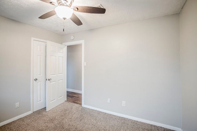 empty room with a ceiling fan, a textured ceiling, baseboards, and carpet flooring