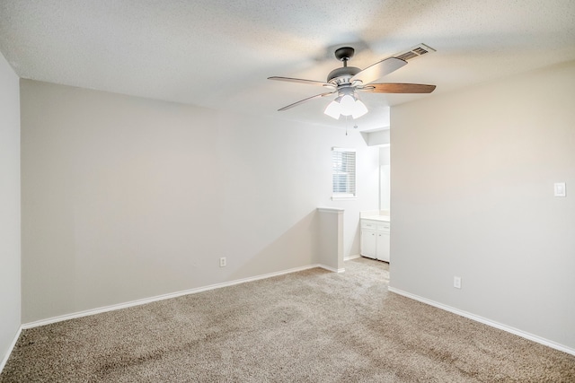 spare room featuring a textured ceiling, light carpet, visible vents, a ceiling fan, and baseboards