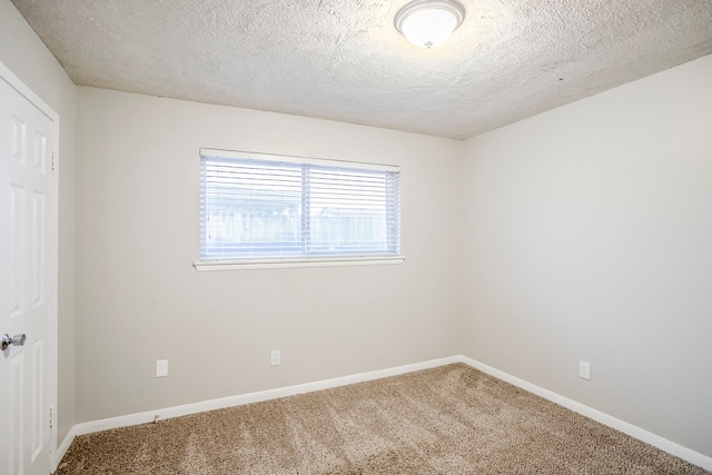 carpeted spare room with a textured ceiling and baseboards