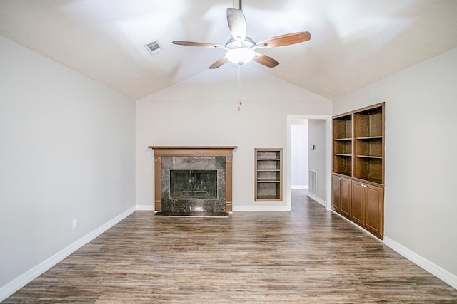 unfurnished living room featuring visible vents, a ceiling fan, wood finished floors, vaulted ceiling, and a high end fireplace