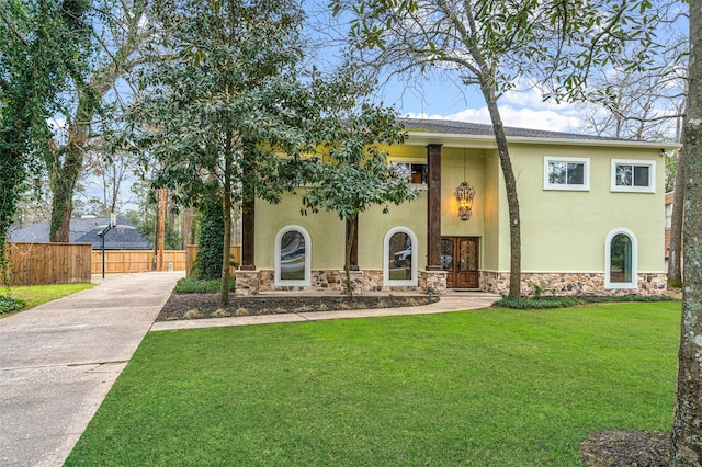 view of front of home featuring stone siding, a front yard, fence, and stucco siding