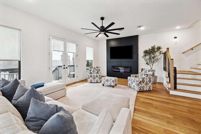 living room featuring visible vents, light wood-style flooring, ceiling fan, stairs, and french doors