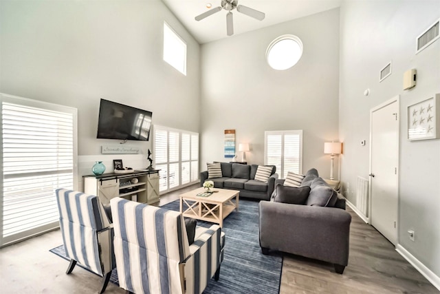 living area with a ceiling fan, baseboards, visible vents, and wood finished floors