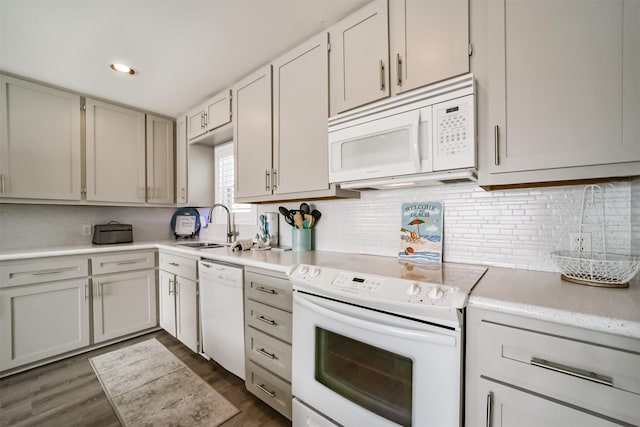 kitchen with white appliances, dark wood-style flooring, a sink, light countertops, and backsplash