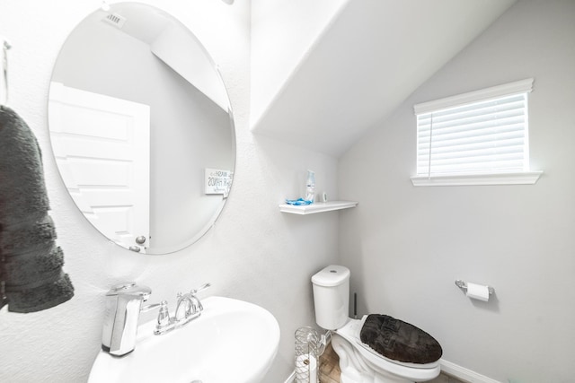 bathroom with vaulted ceiling, a sink, toilet, and baseboards