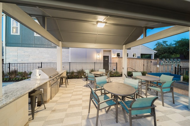 view of patio with an outdoor kitchen, a grill, fence, outdoor dining area, and a bar