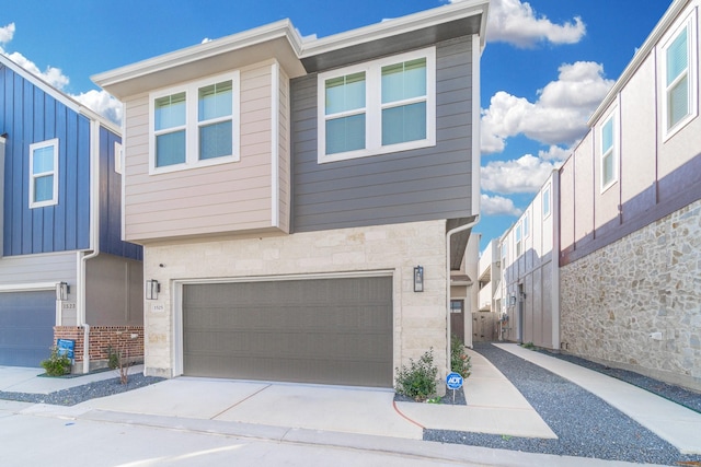 view of front of home featuring an attached garage, driveway, and stone siding