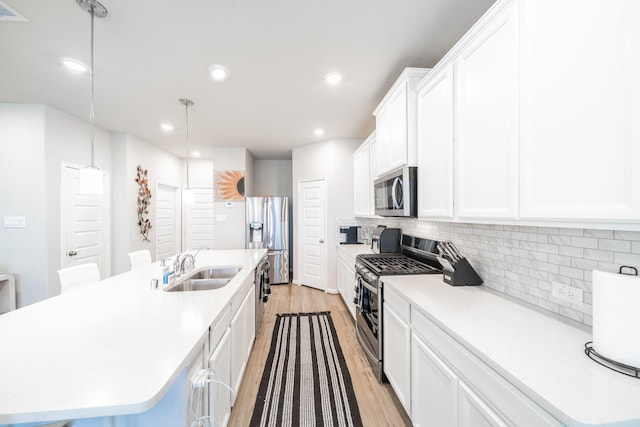 kitchen with light countertops, appliances with stainless steel finishes, and a center island with sink