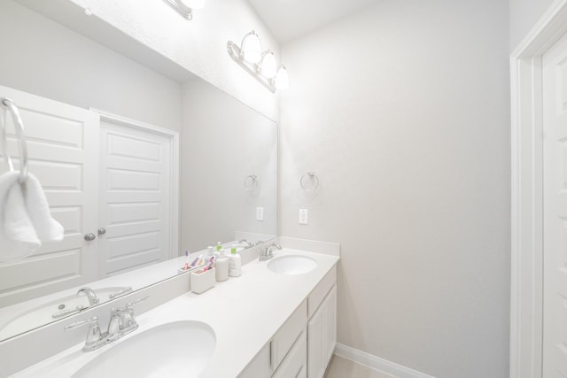 full bathroom featuring a sink, baseboards, and double vanity