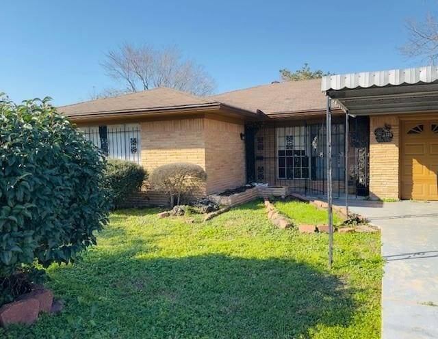 view of front of home featuring brick siding, a front lawn, and an attached garage