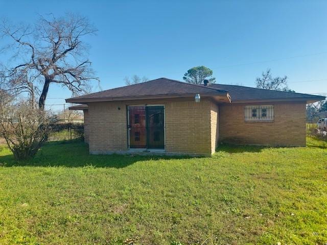 rear view of property with brick siding and a yard