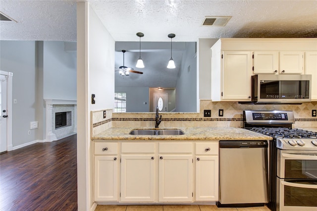 kitchen with stainless steel appliances, a sink, visible vents, white cabinetry, and hanging light fixtures