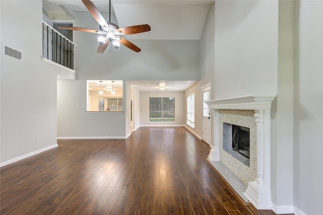 unfurnished living room featuring a fireplace with flush hearth, a ceiling fan, visible vents, baseboards, and dark wood finished floors