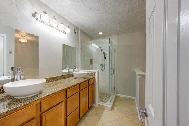 bathroom featuring a textured ceiling, double vanity, a sink, and visible vents