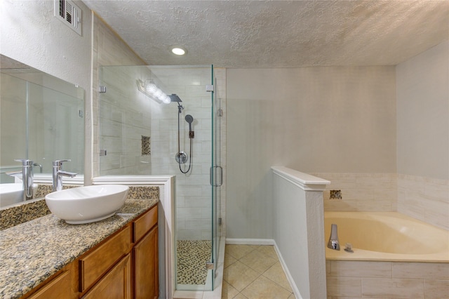 bathroom with a textured ceiling, tile patterned flooring, vanity, visible vents, and a bath