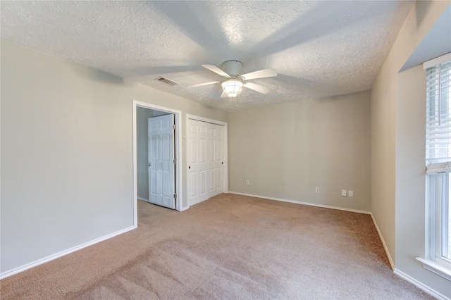 unfurnished bedroom with light colored carpet, visible vents, ceiling fan, a textured ceiling, and baseboards