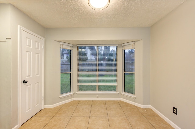 unfurnished room with a healthy amount of sunlight, baseboards, and light tile patterned flooring