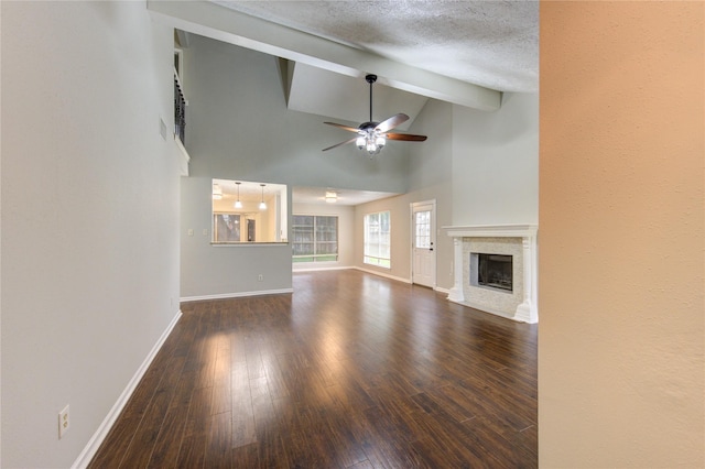 unfurnished living room featuring baseboards, a fireplace with flush hearth, dark wood-type flooring, a textured ceiling, and beam ceiling