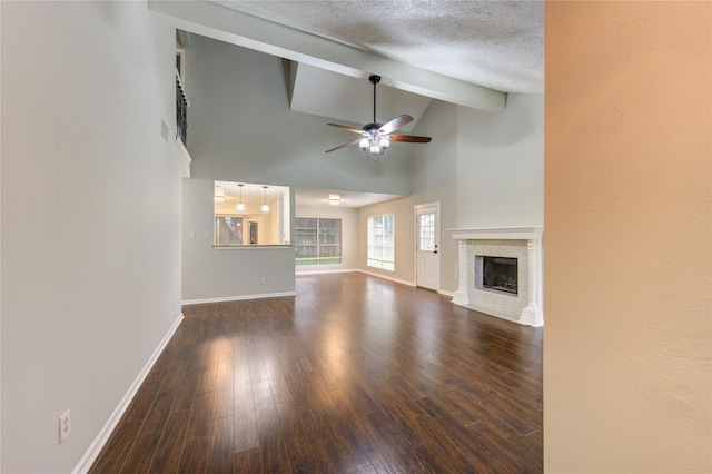unfurnished living room with wood finished floors, beam ceiling, a fireplace, baseboards, and a ceiling fan