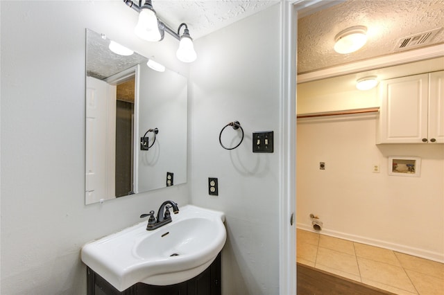 bathroom featuring baseboards, visible vents, tile patterned floors, a textured ceiling, and a sink