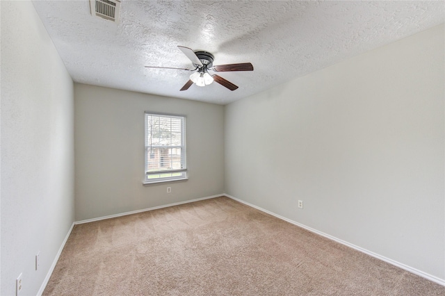 carpeted spare room with visible vents, a textured ceiling, ceiling fan, and baseboards