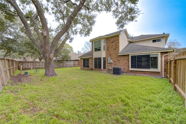 rear view of house featuring brick siding, a lawn, a fenced backyard, and central air condition unit