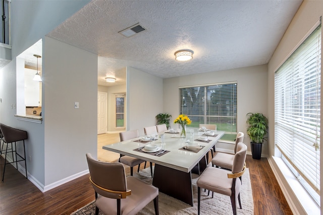 dining area with visible vents, a textured ceiling, dark wood-style flooring, and baseboards