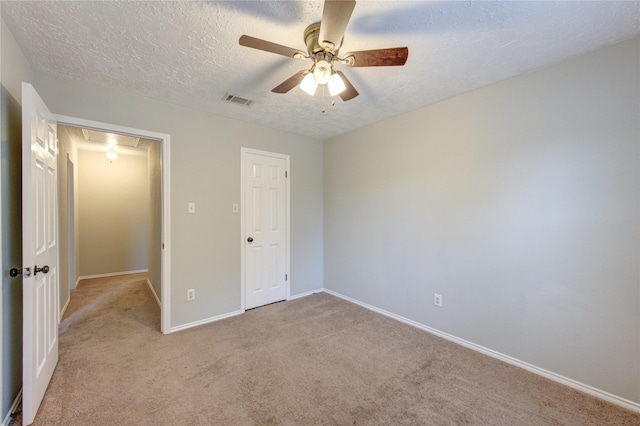 unfurnished bedroom with a textured ceiling, carpet, attic access, baseboards, and visible vents