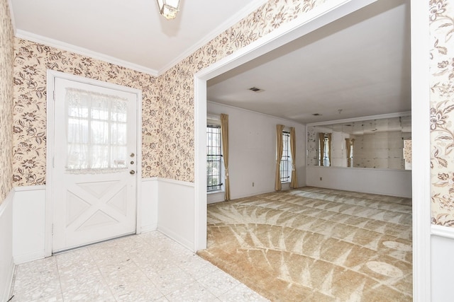 foyer entrance with wallpapered walls, ornamental molding, and a wainscoted wall