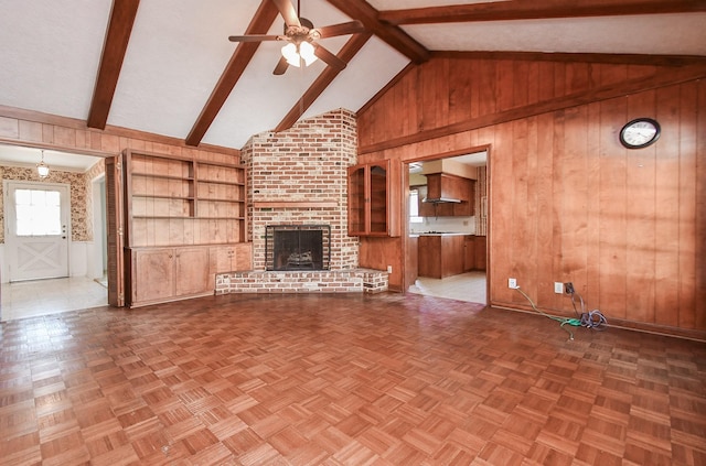 unfurnished living room with a fireplace, wooden walls, and beamed ceiling