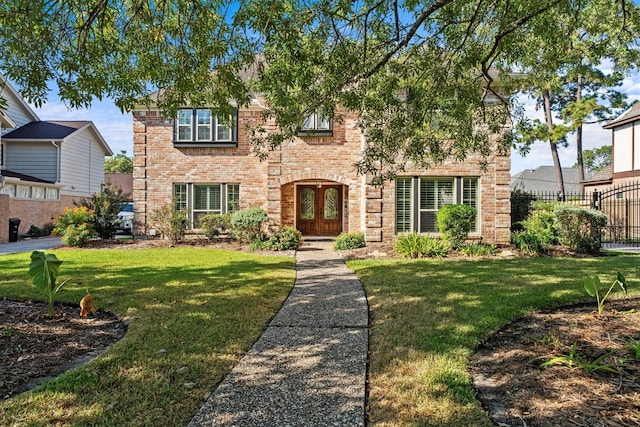 view of front facade featuring french doors, a front lawn, fence, and brick siding