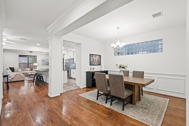 dining space featuring decorative columns, ornamental molding, wood finished floors, and visible vents