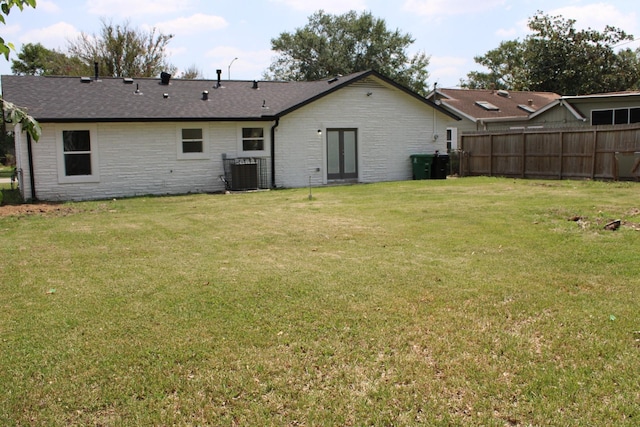 rear view of house featuring a yard, cooling unit, and fence