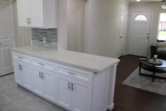 kitchen with light wood finished floors, backsplash, white cabinetry, and light stone countertops