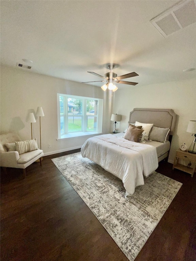 bedroom with ceiling fan, dark wood finished floors, visible vents, and baseboards