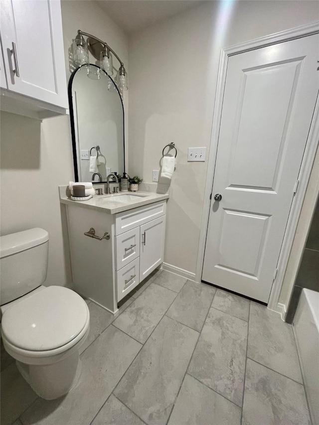 bathroom with vanity, toilet, and baseboards