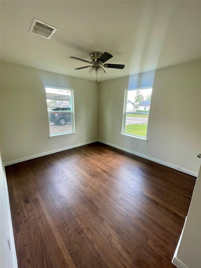 unfurnished room with dark wood-style flooring, plenty of natural light, visible vents, and baseboards