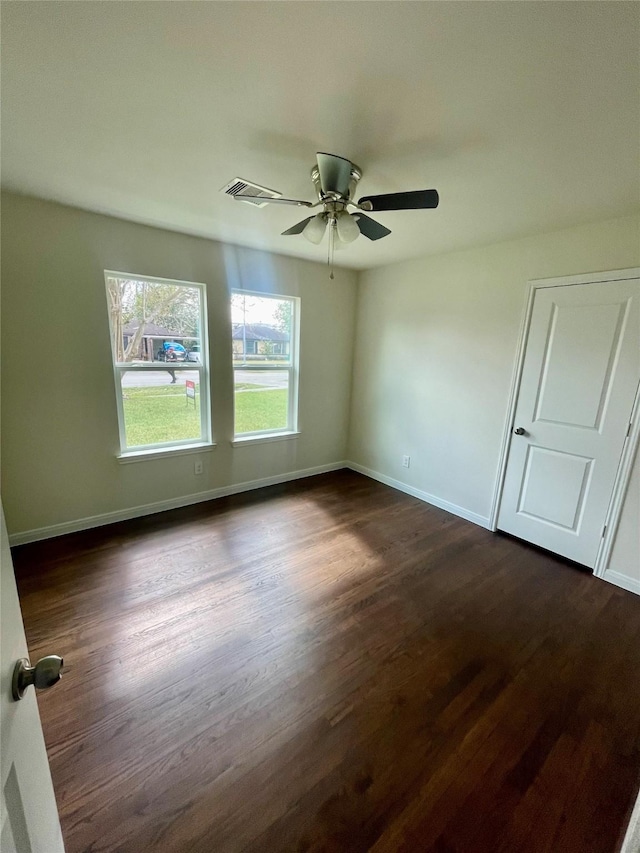 empty room featuring dark wood-style floors, ceiling fan, and baseboards