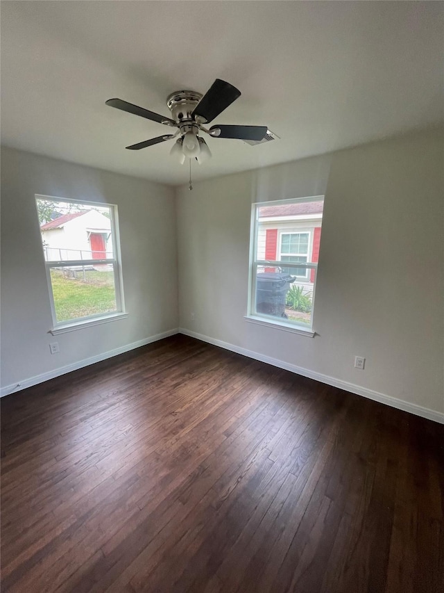 spare room featuring dark wood-type flooring, ceiling fan, and baseboards