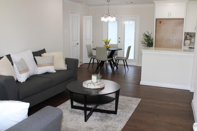 living room featuring an inviting chandelier, baseboards, ornamental molding, and dark wood finished floors