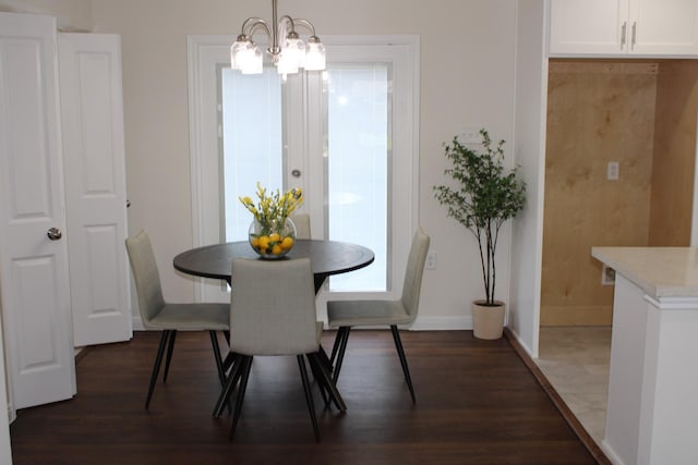 dining area featuring a notable chandelier, dark wood finished floors, and baseboards