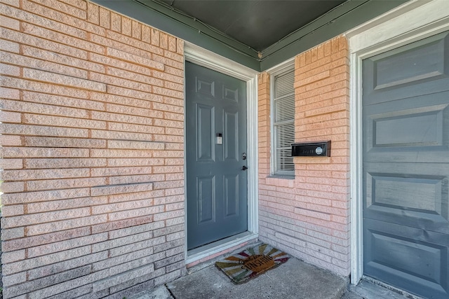 entrance to property featuring a garage and brick siding