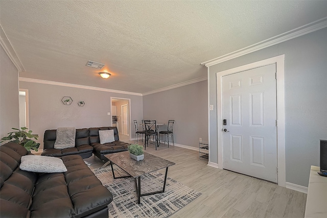 living room featuring a textured ceiling, ornamental molding, light wood-type flooring, and visible vents