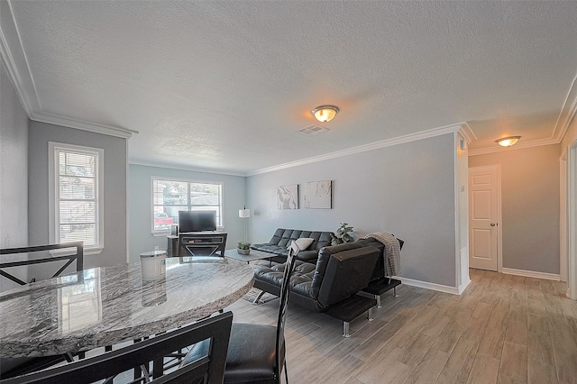 living room with ornamental molding, visible vents, and light wood-style flooring