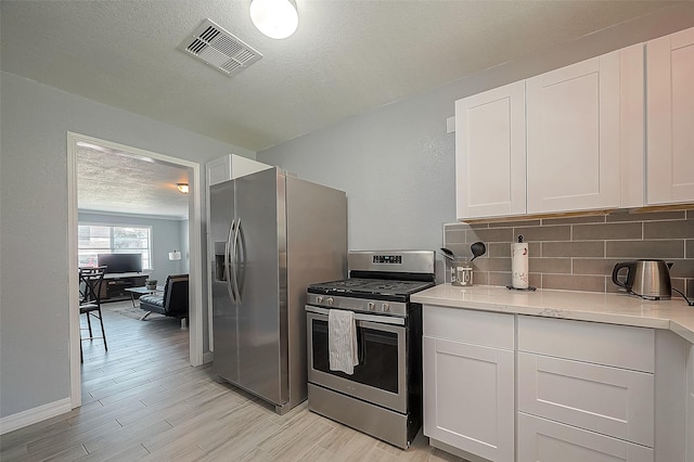 kitchen with white cabinetry, appliances with stainless steel finishes, light countertops, and decorative backsplash