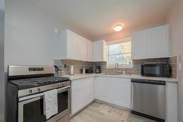 kitchen featuring a sink, stainless steel appliances, light countertops, and white cabinets